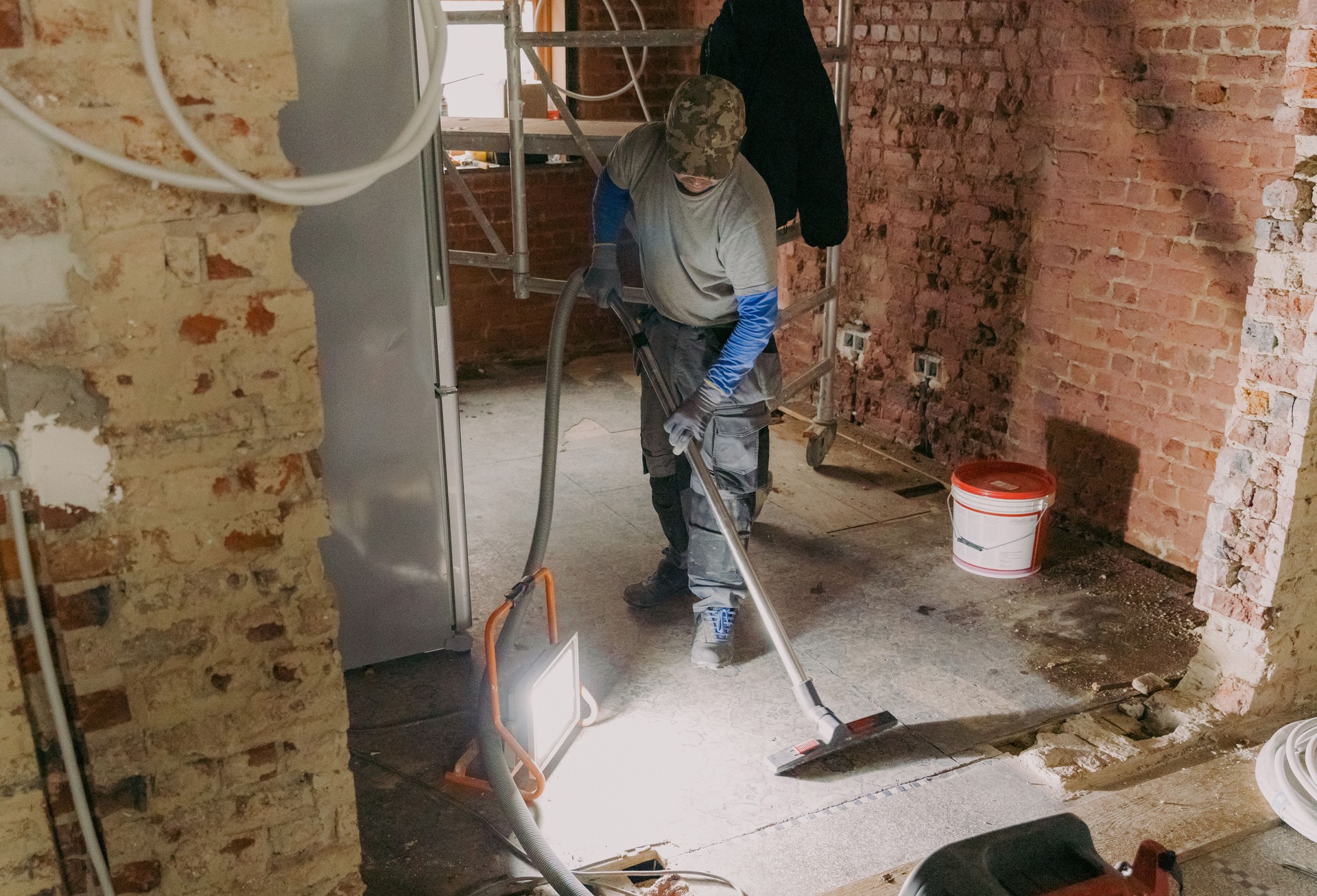 A young man vacuums the landing in a repair room.